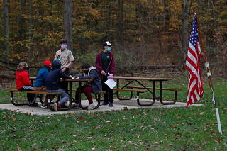 Youth members of the Boys Scouts troop 309 stand next to a U.S. flag wearing protective face mask at Henry Church Rock picnic area in Bentleyville, Ohio