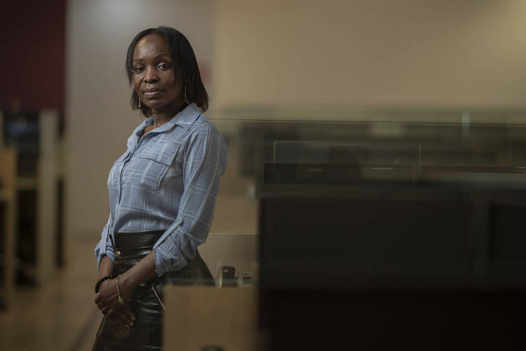 De pé, a assistente jurídica Price Winfred Nalutaaya no escritório que a contratou por meio de programa de diversidade
