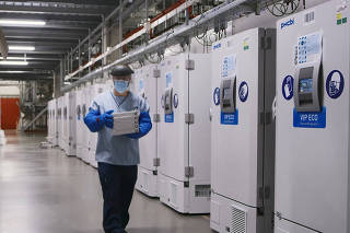FILE PHOTO: A worker passes a line of freezers holding coronavirus disease (COVID-19) vaccine candidate BNT162b2 at a Pfizer facility in Puurs