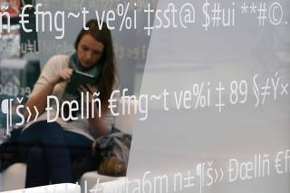 A woman uses a tablet device as she sits at the booth of high security mobile phone software provider Secusmart during preparations at the CeBit computer fair in Hanover