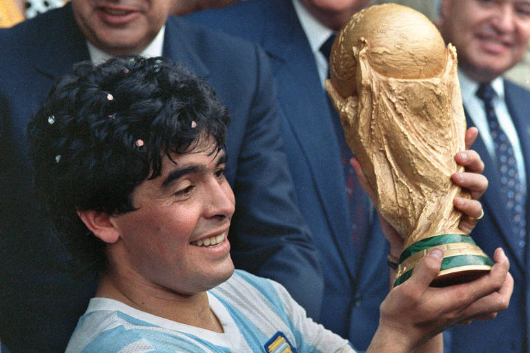Sorrindo, Maradona segura com as duas mãos a Taça Fifa depois da conquista da Copa do Mundo de 1986, no estádio Azteca, na Cidade do México
