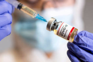 FILE PHOTO: FILE PHOTO: A woman holds a medical syringe and a small bottle labeled 