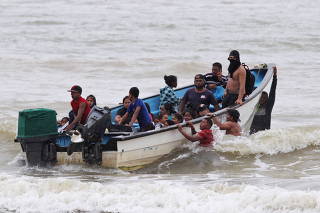 Venezuelan migrants, who were recently deported, arrive at shore on Los Iros Beach after their return to the island, in Erin