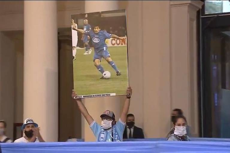 Homem exibe foto de Maradona durante velório do ex-jogador