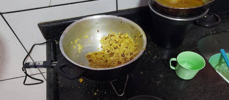 Resto de comida preparada somente com arroz e feijão num aquecedor elétrico improvisado