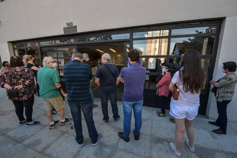 Pessoas aguardam em frente a Puc de São Paulo no segundo turno das eleições municipais no Brasil