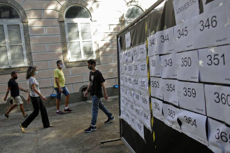 Pessoas passam por um quadro com números de zonas eleitorais durante o segundo turno das eleições municipais no bairro do Flamengo, no Rio de Janeiro