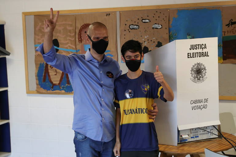 Bruno Covas, prefeito de São Paulo, gesticula enquanto posa com seu filho após votar em uma seção eleitoral durante o segundo turno das eleições municipais em São Paulo