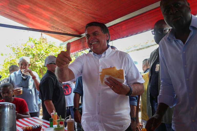 O presidente do Brasil, Jair Bolsonaro, come pastel em feira, após votar durante as eleições municipais no Rio de Janeiro