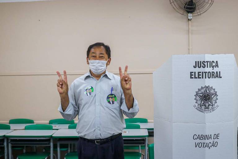 Aprigio fazendo sinal de vitória ao lado da cabine de votacao