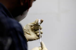 A medic fills a syringe with COVAXIN, an Indian government-backed experimental COVID-19 vaccine, before administering it to a health worker during its trials, in Ahmedabad