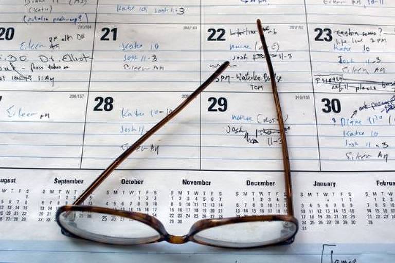 Imagem mostra uma armação de óculos em cima de um calendário com anotações nos dias