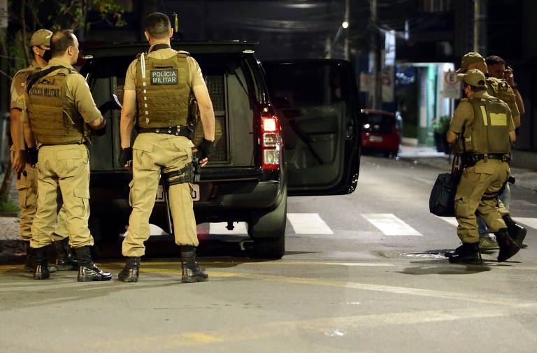 Policiais carregam sacolas recuperadas com dinheiro, após gangue assaltar um Banco do Brasil em Criciúma