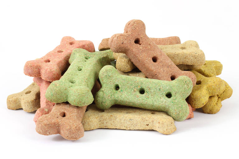 Pilha de biscoitos caninos em forma de ossinhos verde, laranja e amarelo