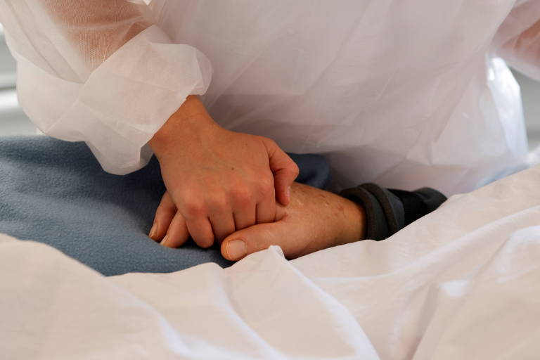 Enfermeira segura mão de paciente