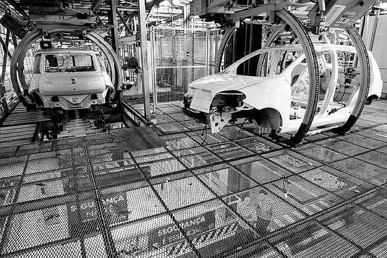 Carcaças de carros suspensas por garras em fábrica de automóveis