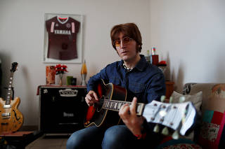 Javier Parisi, who impersonates late former Beatle John Lennon, plays the guitar during an interview with Reuters, in Lanus, on the outskirts of Buenos Aires