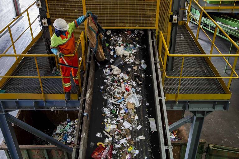 Funcionários manuseiam e separam o lixo reciclado em central de triagem em São Paulo