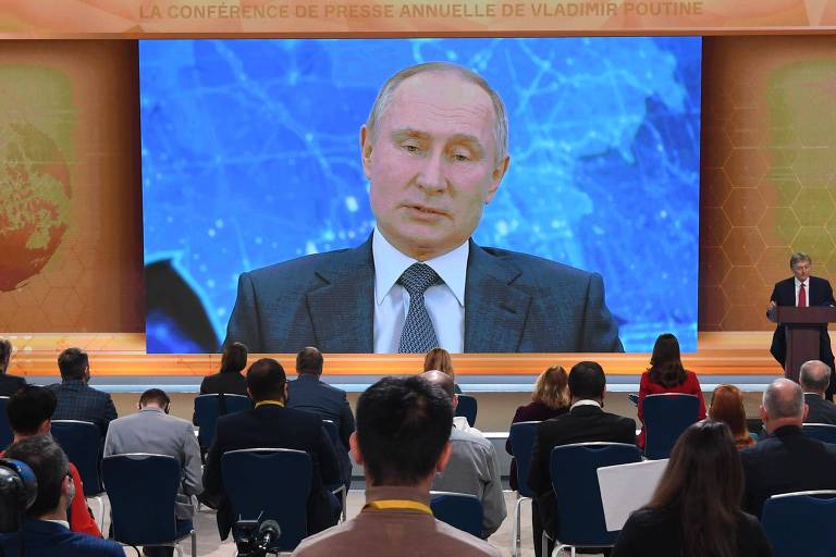 No palco, o porta-voz Dmitri Peskov seleciona perguntas para Putin, que fez sua entrevista coletiva anual remotamente de sua casa nos arredores de Moscou.