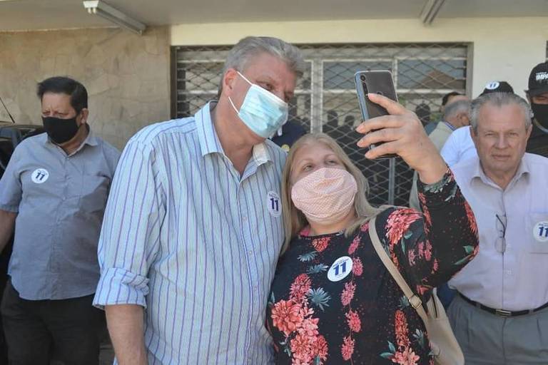 Homem com máscara tira foto com mulher com máscara durante a campanha eleitoral