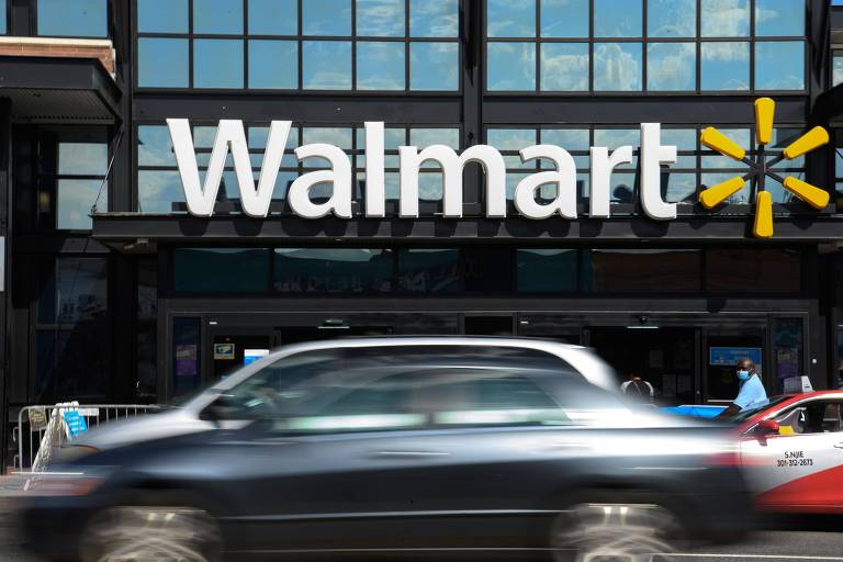 Carro preto passa em frente a loja com símbolo do Walmart 