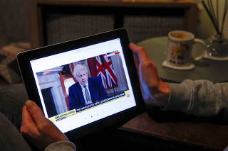 Teacher Wendy Couldridge watches on a device as Britain's Prime Minister Boris Johnson announces a lockdown in England