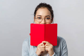 Education, university and people concept. Close-up portrait of romantic young female student, asian girl have secret diary, hiding smile behind planner or notebook, writing notes, grey background