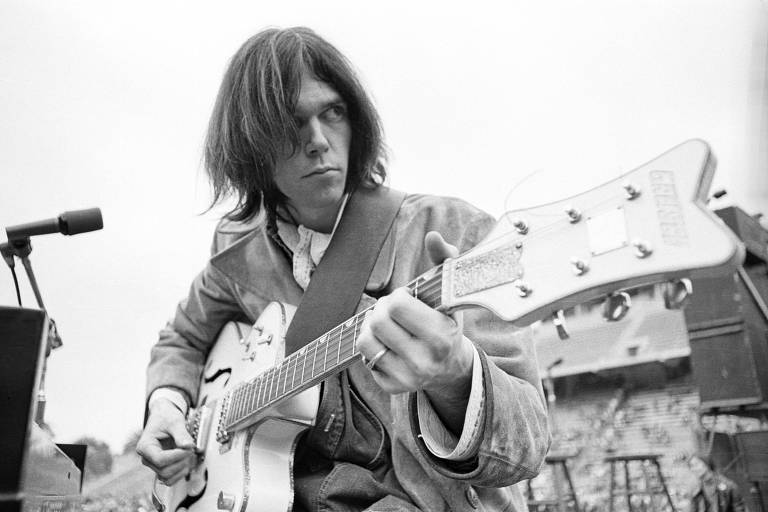 Foto em preto e branco de Neil Young tocando guitarra