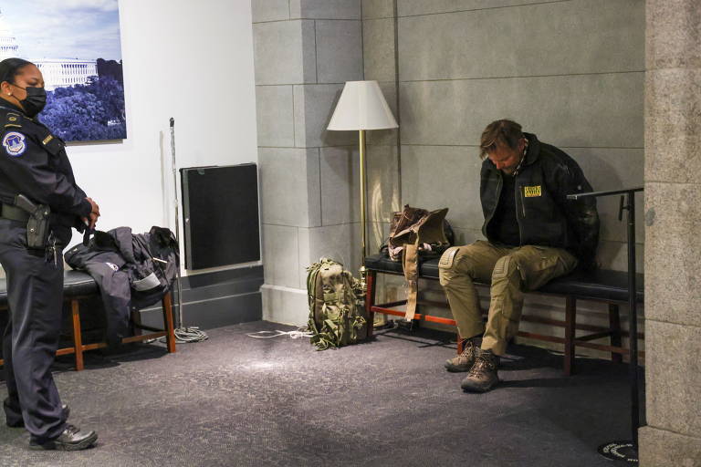 Um policial vigia um manifestante detido dentro do prédio do Congresso em Washington