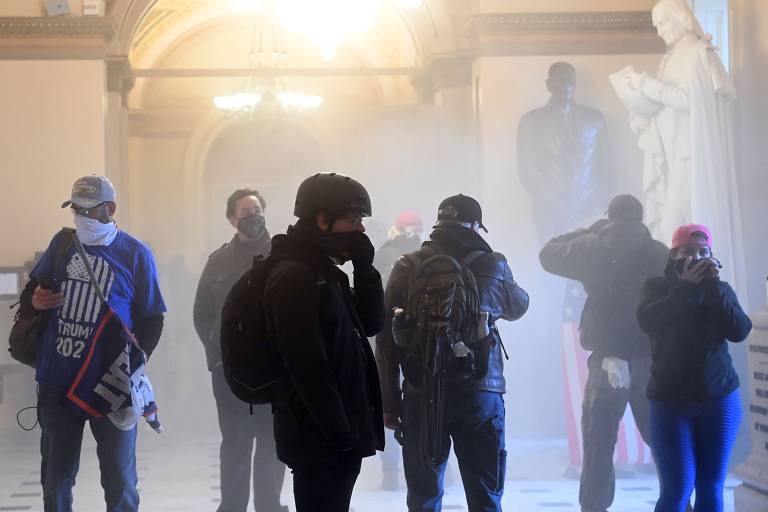 Apoiadores de Donald Trump entram no prédio do Congresso americano enquanto a polícia lança bombas de gás lacrimogêneo