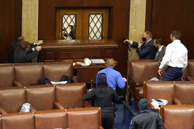 Agentes de segurança apontam arma para porta por onde manifestantes entraram no plenário