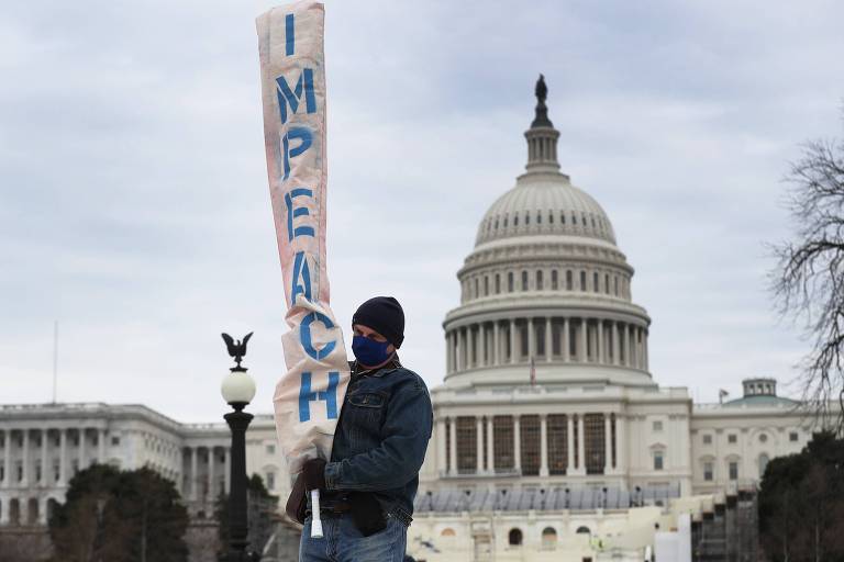 Em frente ao Capitólio, manifestante carrega faixa que defende impeachment do presidente Donald Trump 
