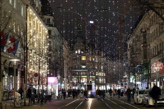 People walk under Christmas illuminations at the Bahnhofstrasse shopping street in Zurich