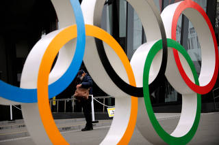 FILE PHOTO: Man is seen through the Olympic rings in Tokyo