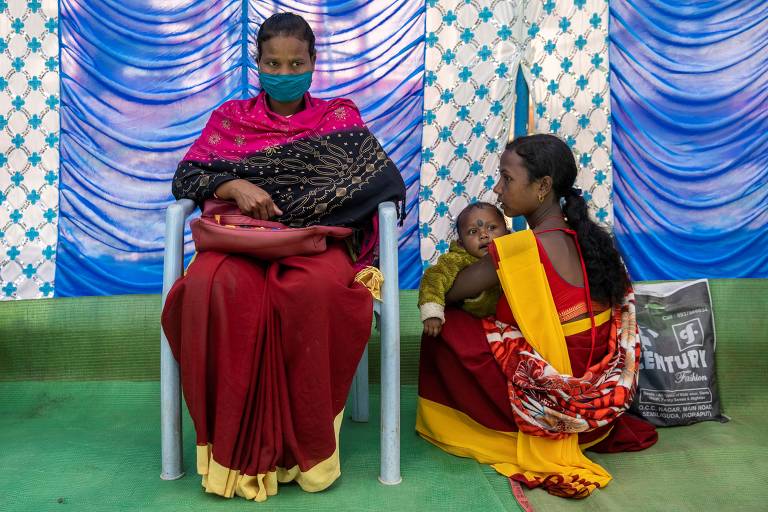 Profissionais de saúde indianas aguardam em fila de vacinação em centro comunitário na remota cidade de Koraput