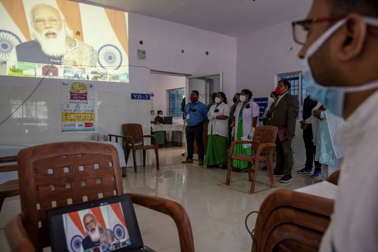 Profissionais de saúde de Koraput assistem a depoimento do primeiro-ministro indiano, Narendra Modi, falando sobre o início da campanha de vacinação do país