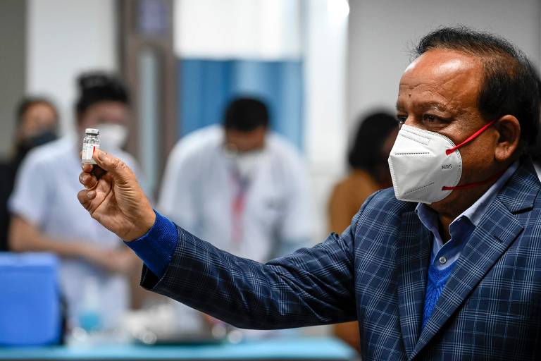 O ministro da Saúde da Índia, Harsh Vardhan, chega a centro de saúde de Nova Déli e exibe frasco com vacina contra a Covid-19 para celebrar início da campanha de vacinação no país