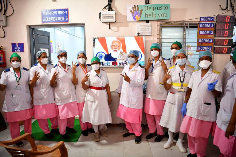 Enfermeiras do hospital Rajawadi, em Mumbai, fazem símbolo da vitória para celebrar início da campanha de vacinação na Índia após assistirem a depoimento de Narendra Modi