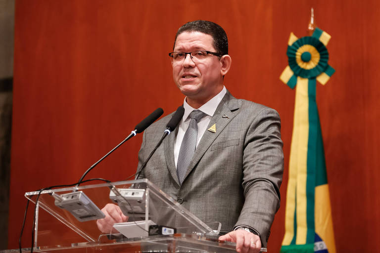  Marcos José Rocha dos Santos aparece em pé, em frente a microfones