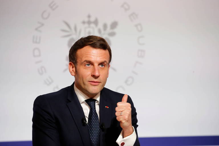 O presidente da França faz sinal de positivo com o polegar, de terno prego e gravata escura
