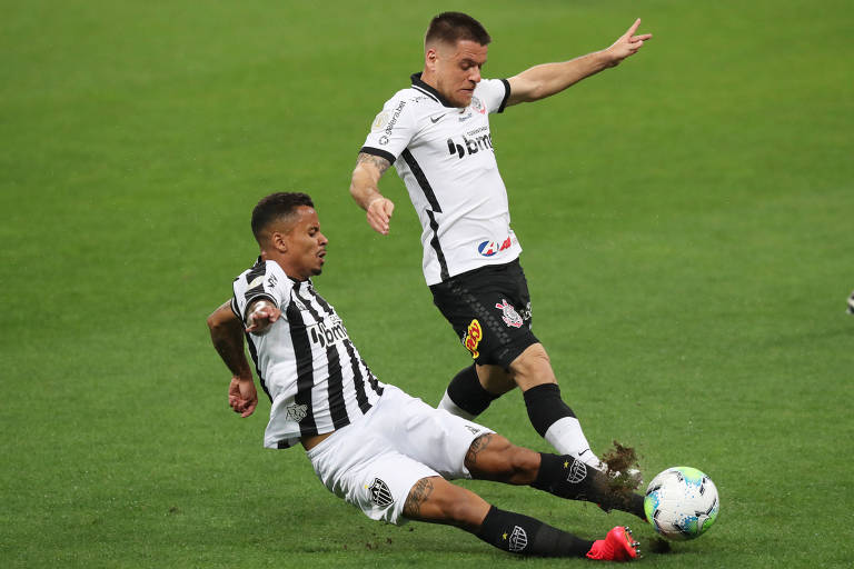 Dois jogadores com uniformes preto e branco disputam uma bola 