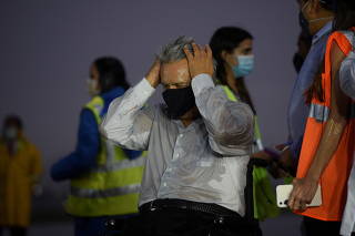 Ecuador's President Lenin Moreno reacts in the rain after the arrival of a first batch of doses of COVID-19 vaccines from Pfizer, as the outbreak of the coronavirus disease continues, in Guayaquil