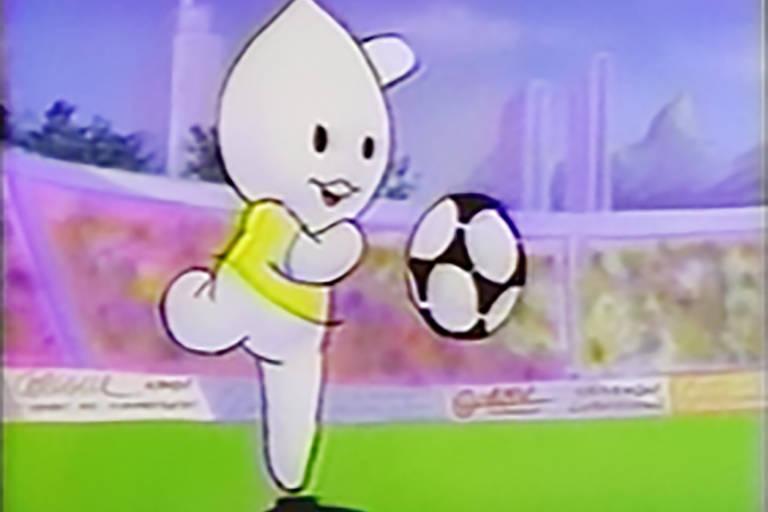 Uma cena de um desenho animado mostra o personagem Zé Gotinha de camiseta amarela, no gramado de um estádio de futebol. Ele está prestes a dar um chute em uma bola preta e branca