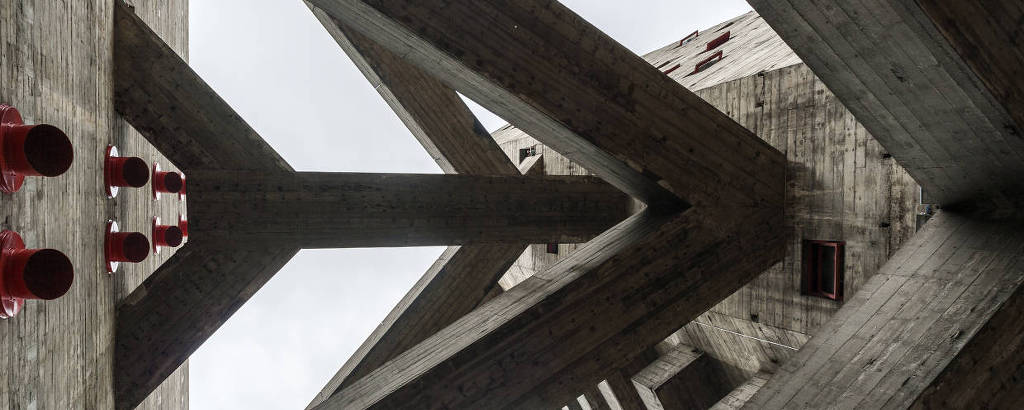 A foto é feita do térreo para o alto e mostra as passarelas de concreto em forma de V ou seta que ligam dois prédios