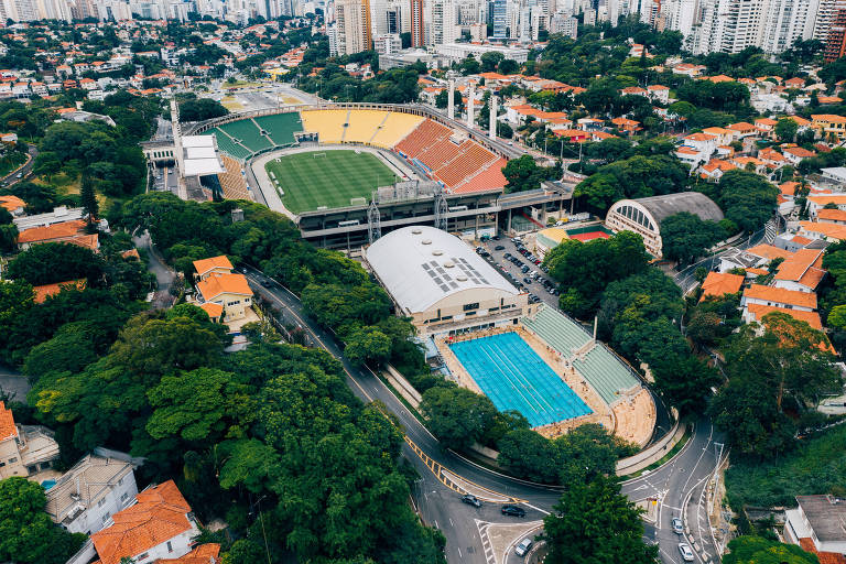 A piscina do Pacaembu e o estádio, ao fundo. O tobogã é a arquibancada mais próxima à parte aquática do local