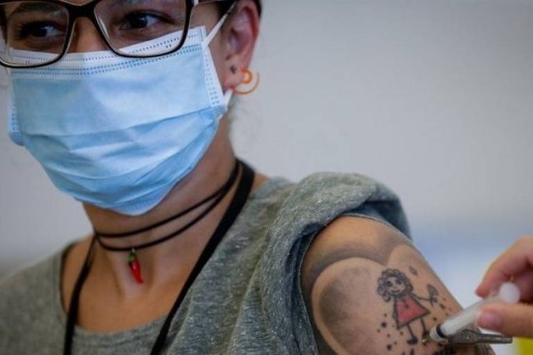 Mulher com máscara recebe vacina