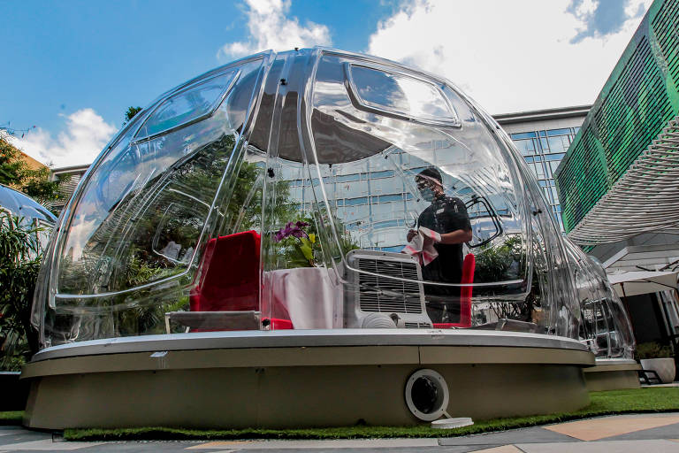 Garçom de hotel em Manila, nas Filipinas, faz serviço à mesa em bolha, ação contra a Covid