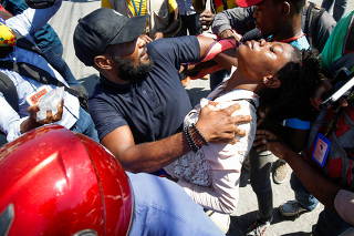 Journalists help a colleague who fainted after police threw tear gas during a protest against Haiti's President Jovenel Moise, in Port-au-Prince