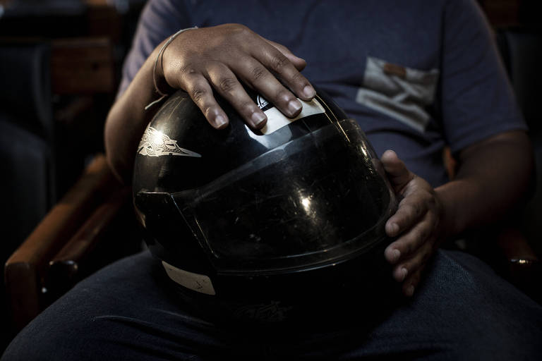 Durante entrevista à Folha, Paulo Lima, o Galo, segura o capacete que usa nas entregas