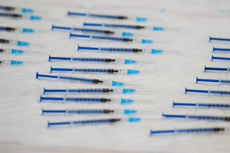 várias seringas finas, com êmbolo azul e suporte de agulha azul claro, sobre tampo branco